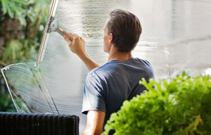 a man squeegees window solution on glass