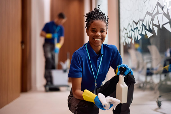 woman smiles while holding cleaning towel and spray bottle